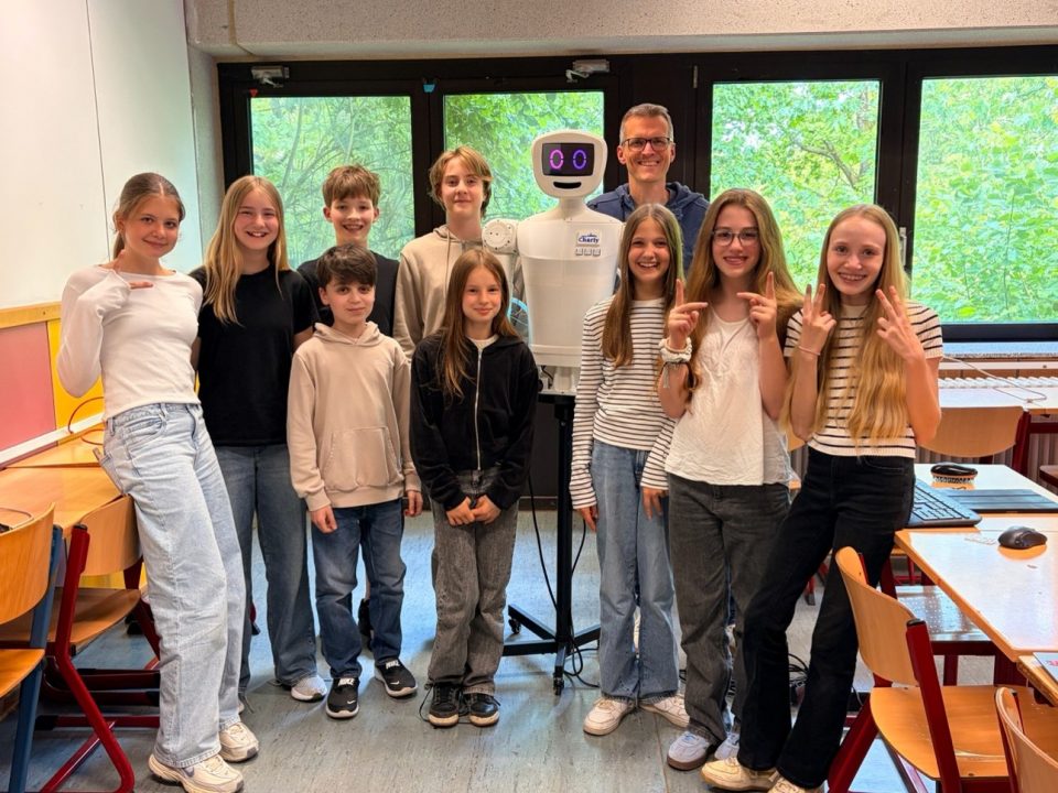 Ein Gruppe Schülerinnen nund Schüler stehen neben einem selbst gebauten, humanoiden Roboter.