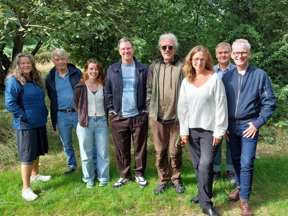 Eine Gruppe von Menschen, die einen Garten, der einer Stiftung gehört besuchen und sich deren Ideen und deren Arbeit erklären lassen. Auf dem Bild sind drei Frauen und fünf Männer im Grünen zu sehen